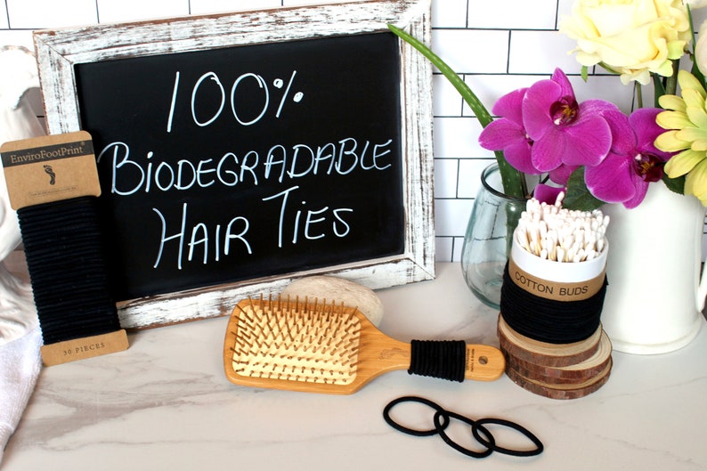 May include: A set of black hair ties, a wooden hair brush, a container of cotton buds, and a chalkboard sign that reads "100% Biodegradable Hair Ties".