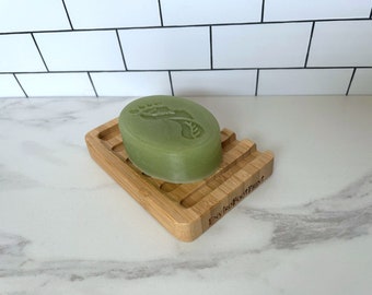 May include: A green soap bar with a footprint design on a bamboo soap dish. The dish has the text "Enviro Footprint" engraved on it.