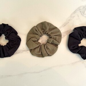 May include: Three fabric scrunchies in black, olive green, and dark green.