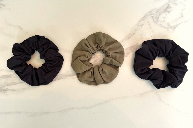 May include: Three fabric scrunchies in black, olive green, and dark green.