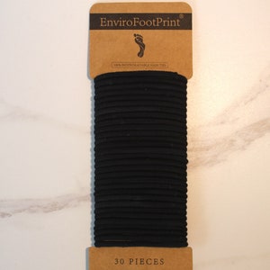 May include: A pack of 30 black hair ties, made from 100% biodegradable natural rubber, with the brand name "EnviroFootPrint" printed on the front.