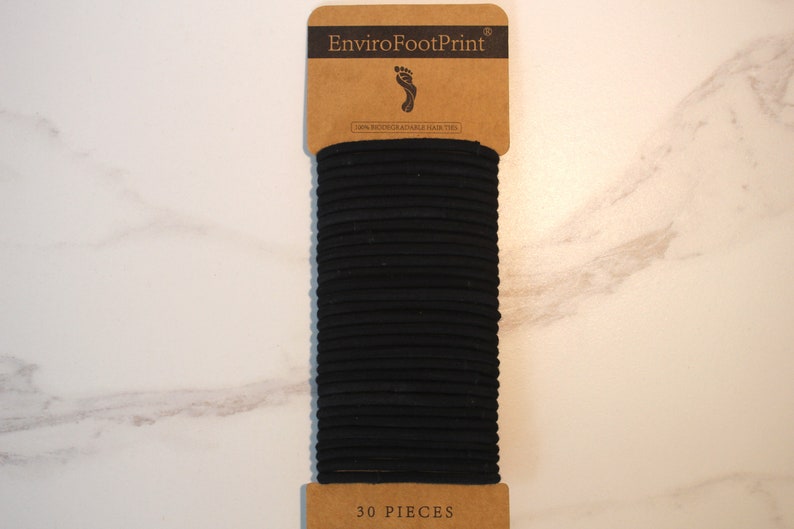 May include: A pack of 30 black hair ties, made from 100% biodegradable natural rubber, with the brand name "EnviroFootPrint" printed on the front.