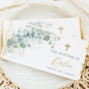 Puede incluir: Caja de regalo blanca con un diseño de acuarela de hojas azules y verdes y detalles dorados. La caja tiene una cruz dorada y el texto "El Bautismo de Dylan ¡Gracias por venir!" impreso en ella.