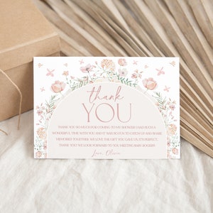 May include: A thank you card with a floral design and the text "thank you" in a pink circle. The card has a pink and white floral border and the text "Thank you so much for coming to my shower. I had such a wonderful time with you and it was so fun to catch up and share memories together. We love the gift you gave us, it's perfect. Thank you! We look forward to you meeting baby Rogers. Love, Olivia."