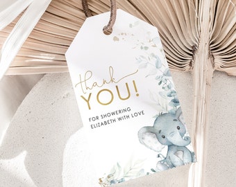 May include: A white tag with a brown string features gold text that reads "Thank You!" and "For Showering Elizabeth With Love." A watercolor illustration of a gray elephant and green foliage decorates the tag, suitable for a baby shower.