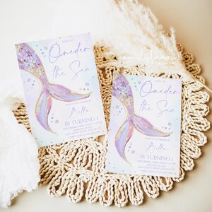 May include: Two purple and gold mermaid tail themed first birthday party invitations with the text "Oneder the Sea" and "Our Little Mermaid Bella is Turning 1".