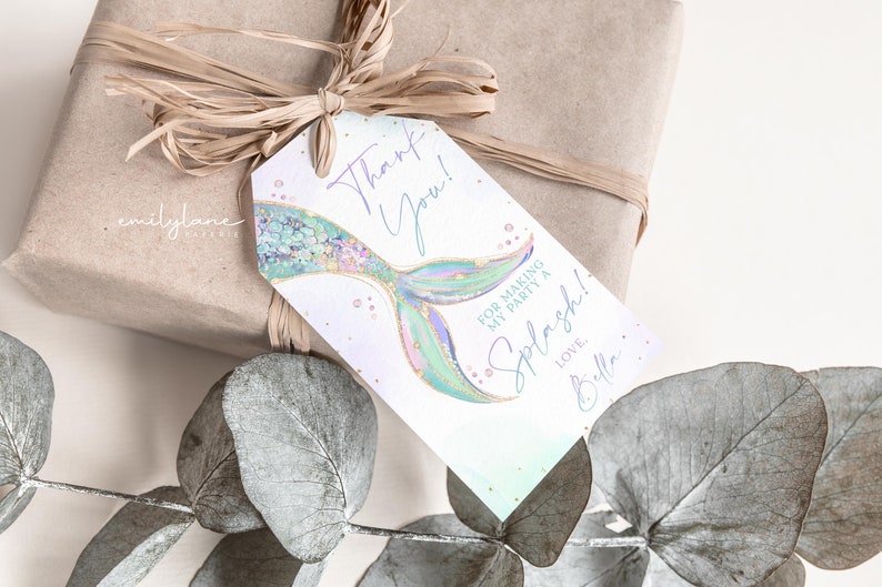 Puede incluir: Una etiqueta de agradecimiento con una ilustraci&oacute;n de cola de sirena. La etiqueta es blanca con un fondo degradado azul claro y verde. El texto en la etiqueta dice "&iexcl;Gracias! Por hacer de mi fiesta un Splash! Con amor, Bella."