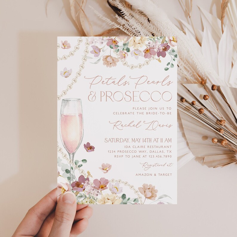 May include: A bridal shower invitation with a floral design and a glass of pink prosecco. The invitation reads "Petals, Pearls & Prosecco" and includes the bride-to-be's name, Rachel Davis, the date and time of the event, and the location. The invitation also includes the text "Registered at Amazon & Target".