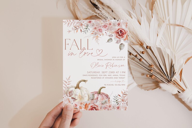 May include: Fall in love bridal shower invitation with a watercolor floral design featuring pumpkins and a heart. The invitation is printed on white cardstock and has a pink and gold color scheme. The text on the invitation reads "Fall in love" and "Join us for a bridal shower in honor of Olivia Robinson".