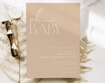 Pode incluir: Um convite de chá de bebê de cor marrom claro com o texto "oh BABY" em fonte branca cursiva. O convite inclui o nome "hannah davis" e os detalhes do evento, incluindo a data, hora, local e informações de RSVP. O texto "registered at TARGET & AMAZON" também está incluído.