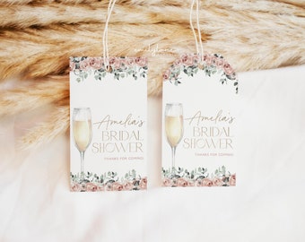 May include: Two white gift tags with a floral design and a champagne glass illustration. The text on the tags reads "Amelia's Bridal Shower Thanks for coming!"