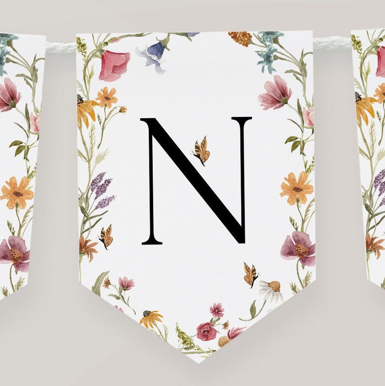 K&ouml;nnte beinhalten: Ein wei&szlig;es Banner mit einem floralen Rand und dem Buchstaben "N" in Schwarz in der Mitte. Die Blumen sind in den Farben Rosa, Gelb, Orange und Lila. Es gibt auch kleine Schmetterlinge im Design.