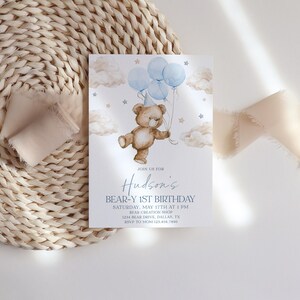 May include: A blue and white birthday invitation with a cartoon teddy bear holding blue balloons. The invitation says "Join us for Hudson's Bear-Y 1st Birthday" and includes the date, time, and location of the party.