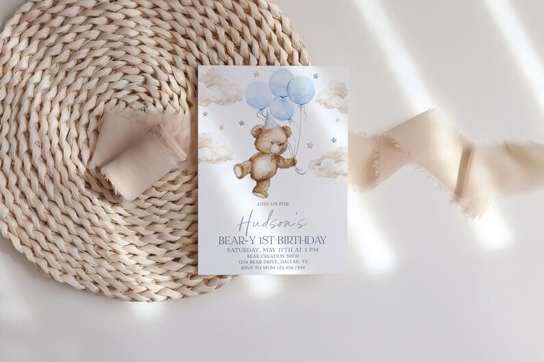May include: A blue and white birthday invitation with a cartoon teddy bear holding blue balloons. The invitation says "Join us for Hudson's Bear-Y 1st Birthday" and includes the date, time, and location of the party.