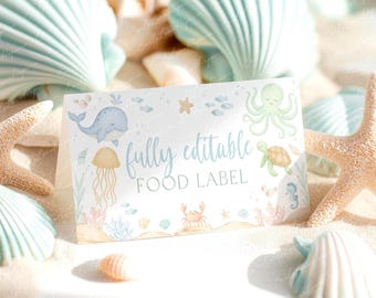 May include: A white, fully editable food label with watercolor illustrations of marine life, including a whale, jellyfish, octopus, and turtle. The label is surrounded by seashells and starfish, creating a beachy theme.