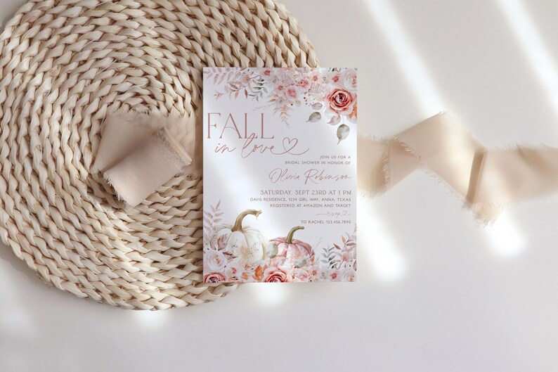 May include: Fall in love bridal shower invitation with a watercolor floral design featuring pumpkins, leaves, and roses in shades of pink and orange. The invitation text reads "Fall in love" with a heart and "Bridal Shower in honor of [Name]" with the date, time, and location.