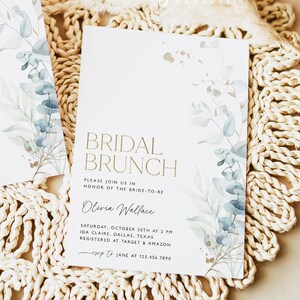 May include: A white invitation card with gold lettering that reads "Bridal Brunch" and features a watercolor illustration of eucalyptus leaves. The invitation is for Olivia Wallace's bridal brunch on October 30th at 2 PM in Ida Claire, Dallas, Texas. The RSVP information is included at the bottom of the card.