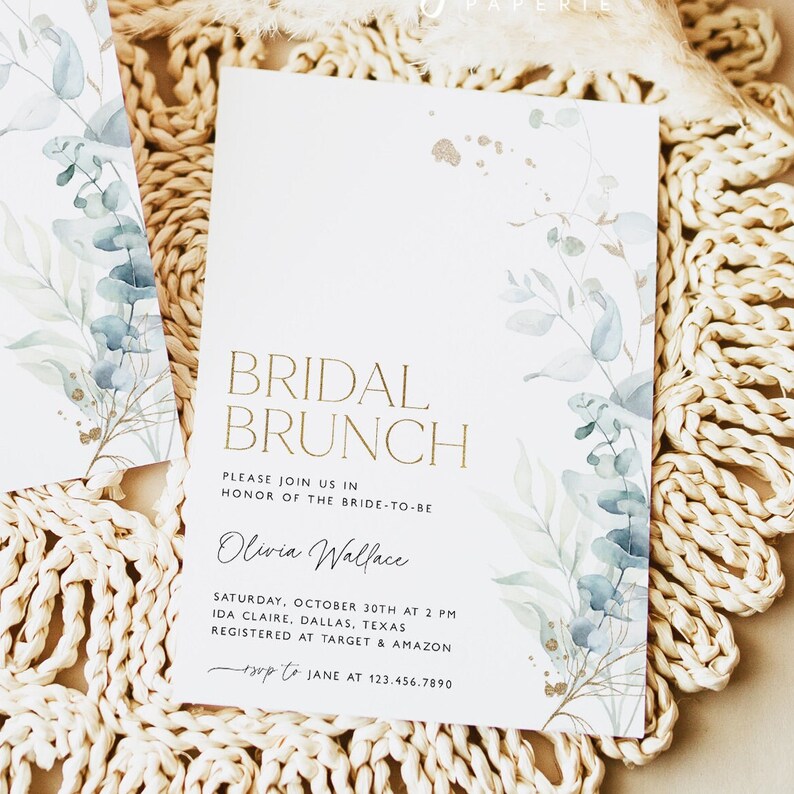 May include: A white invitation card with gold lettering that reads "Bridal Brunch" and features a watercolor illustration of eucalyptus leaves. The invitation is for Olivia Wallace's bridal brunch on October 30th at 2 PM in Ida Claire, Dallas, Texas. The RSVP information is included at the bottom of the card.
