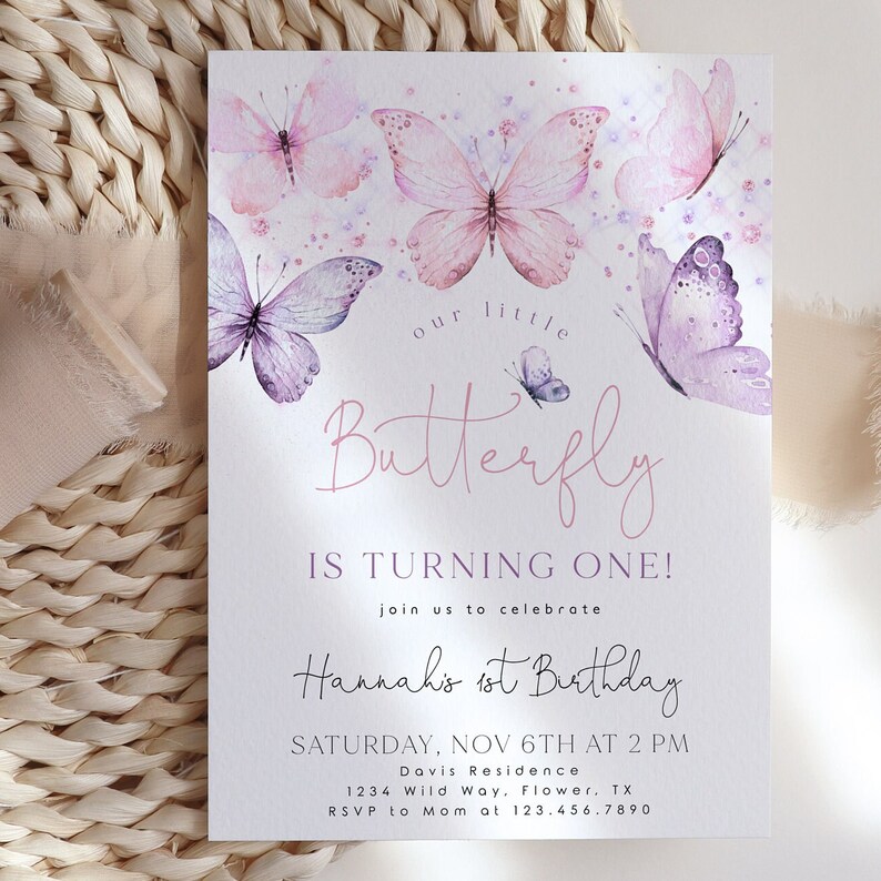 May include: A pink and purple butterfly-themed first birthday party invitation with the text "our little butterfly is turning one!" and "Hannah's 1st Birthday". The invitation includes the date, time, and location of the party.