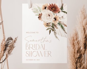 May include: A white sign with a floral design in shades of brown, beige, and white. The text on the sign reads "Welcome to Samantha's Bridal Shower October 30, 2021".