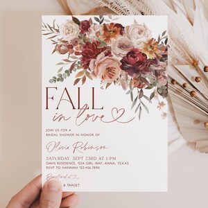 May include: Fall in love bridal shower invitation with a watercolor floral design in shades of burgundy, pink, and orange. The invitation features the text "Fall in love" with a heart symbol and details for the event, including the date, time, location, and RSVP information.