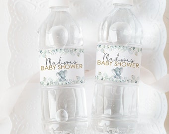 May include: Two clear plastic water bottles with white caps. Each bottle has a label that reads "Madison's BABY SHOWER" in gold script, with a gray elephant illustration. The labels have a floral design in shades of green and blue.