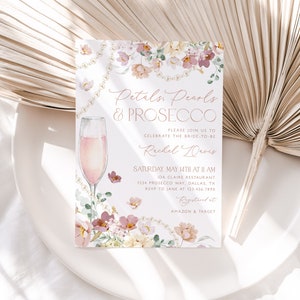 May include: A pink and white floral bridal shower invitation with gold lettering. The invitation reads "Petals, Pearls & Prosecco" and includes details for the event, including the date, time, location, and RSVP information. The invitation also includes a watercolor illustration of a glass of champagne.