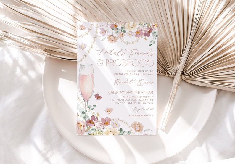 May include: A pink and white floral bridal shower invitation with gold lettering. The invitation reads "Petals, Pearls & Prosecco" and includes details for the event, including the date, time, location, and RSVP information. The invitation also includes a watercolor illustration of a glass of champagne.