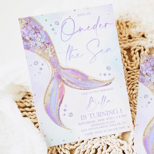 May include: Purple and gold mermaid tail illustration with glitter and stars on a light blue background. The text "Join Us Oneder the Sea" is at the top of the invitation. The text "Our Little Mermaid Bella Is Turning 1" is at the bottom of the invitation. The invitation also includes the date, time, and location of the party.