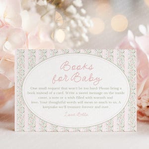 Puede incluir: Tarjeta de invitación para baby shower con el texto "Books for Baby" en escritura rosa suave. La tarjeta tiene un diseño floral y a rayas en rosa y verde, con un marco ovalado que contiene una solicitud de libro.