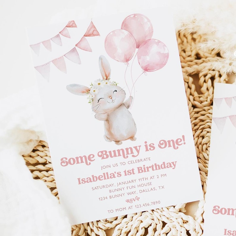 Op de afbeelding: Een roze en witte verjaardagsuitnodiging met een schattig konijn dat roze ballonnen vasthoudt. De uitnodiging luidt "Some Bunny is one!" en bevat de tekst "Isabella's 1st Birthday".