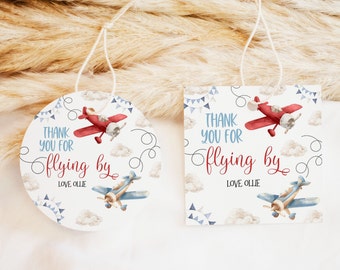 May include: Two round thank you tags with a blue and red airplane design. The text on the tags reads "Thank you for flying by Love Ollie".