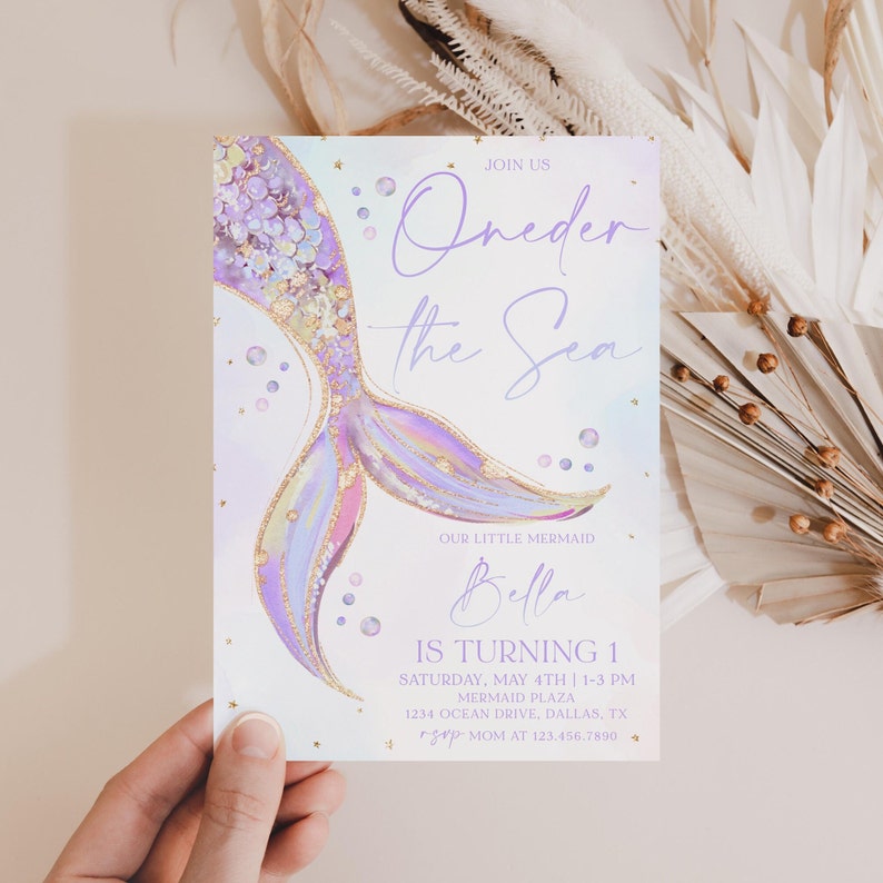 May include: A purple and gold mermaid tail illustration with a sparkly background. The text "Join us Oneder the Sea" is at the top of the invitation. The text "Our little mermaid Bella is turning 1" is at the bottom of the invitation. The invitation also includes the date, time, and location of the party.