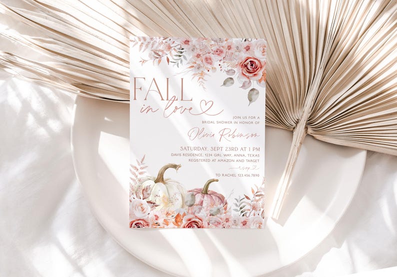 May include: Fall in love bridal shower invitation with a watercolor design featuring pumpkins, flowers, and leaves in shades of pink, white, and green. The text "Fall in love" is written in a script font with a heart symbol. The invitation includes the bride's name, the date and time of the shower, the location, and the registry information.