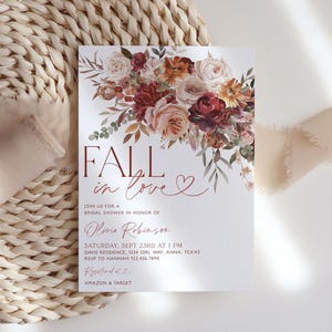 May include: Fall in love bridal shower invitation with a watercolor floral design in shades of burgundy, peach, and cream. The invitation features the text "Fall in love" with a heart symbol. The text also includes the bride's name, date, time, and location of the shower.