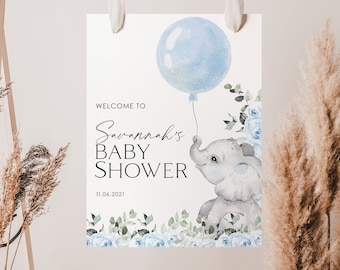 May include: A blue and white baby shower sign featuring a cute elephant holding a blue balloon. The sign reads "Welcome to Savannah's Baby Shower 11.06.2021".