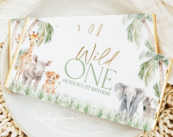 May include: A rectangular invitation with a safari theme. The invitation features the text "Wild One" in gold and green, with illustrations of a giraffe, lion, elephant, and zebra. The text "Jackson's 1st Birthday" is also included.