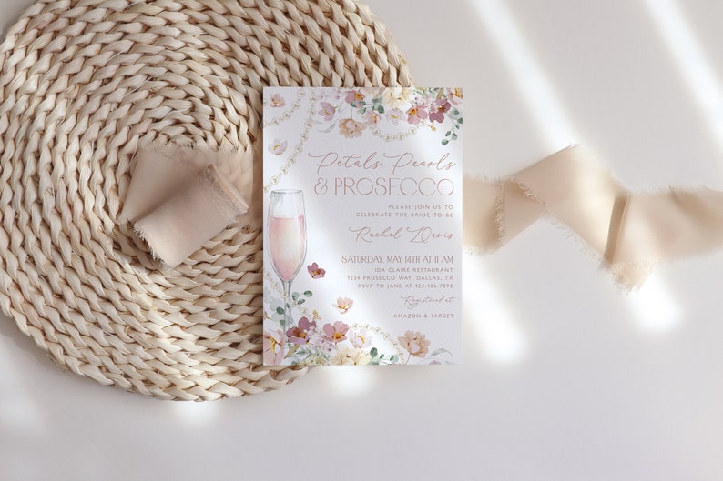 May include: A floral-themed bridal shower invitation with a glass of pink prosecco. The invitation reads "Petals, Pearls & Prosecco" and includes the bride-to-be's name, date, time, and location. The invitation also includes the text "RSVP to Jane at [phone number]" and "Registered at Amazon & Target".