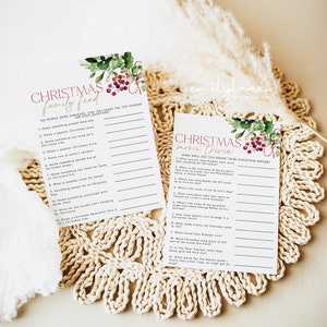 May include: Two printable Christmas game cards with a watercolor floral design featuring red berries and green leaves. The first card is titled "Christmas Family Feud" and includes 12 questions. The second card is titled "Christmas Movie Trivia" and includes 12 questions about popular Christmas movies.