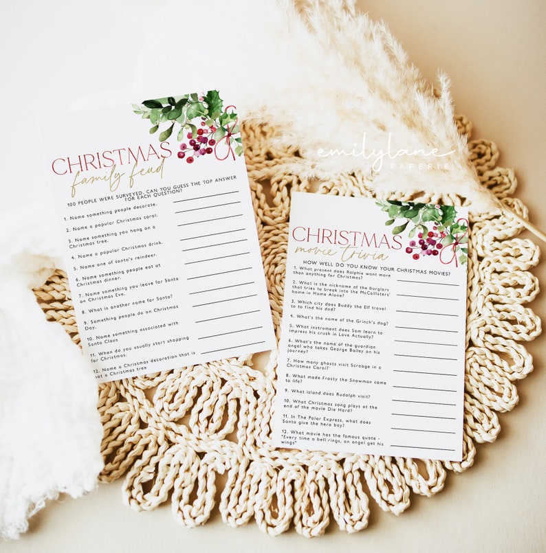 May include: Two printable Christmas game cards with a watercolor floral design featuring red berries and green leaves. The first card is titled "Christmas Family Feud" and includes 12 questions. The second card is titled "Christmas Movie Trivia" and includes 12 questions about popular Christmas movies.