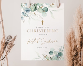 May include: A white sign with gold text and watercolor eucalyptus and gold accents. The sign reads "Welcome to the Christening of our Son" with the name "Kaleb Jackson" and the date "March 12, 2022".
