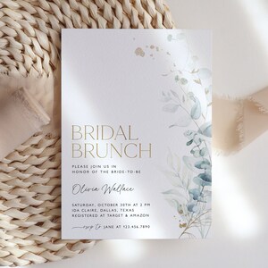 May include: A white invitation card with gold lettering for a bridal brunch. The card features a watercolor illustration of eucalyptus leaves and gold accents. The text reads "Bridal Brunch", "Please join us in honor of the bride-to-be Olivia Wallace", "Saturday, October 30th at 2 PM", "Ida Claire, Dallas, Texas", "Registered at Target & Amazon", "RSVP to Jane at 123.456.7890".