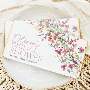 Op de afbeelding: Witte bedankbox met een bloemenontwerp in roze, groene en gele tinten. De tekst "Olivia's Bridal Shower Thanks for Coming!" is in roze op de doos gedrukt. De onderkant van de doos heeft de tekst "emilylane paperie".