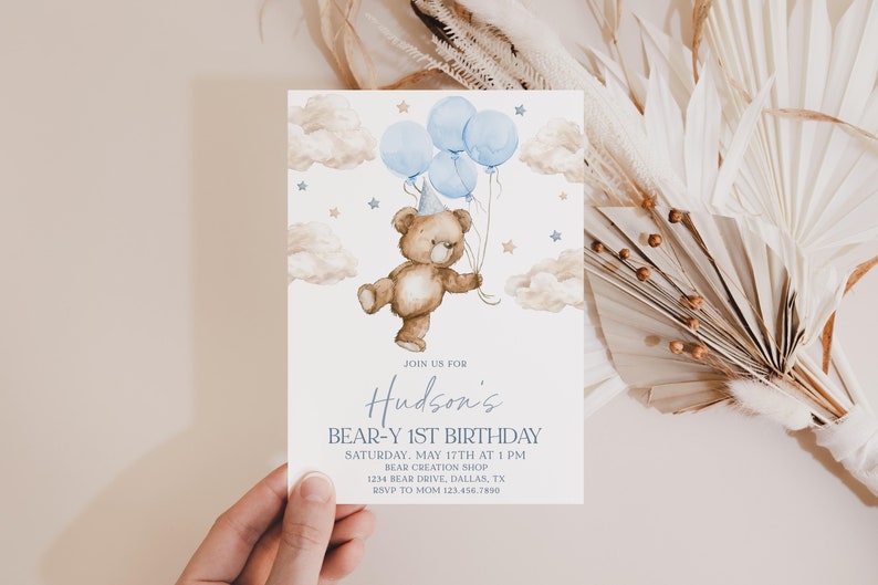 May include: A blue and brown birthday invitation with a cartoon bear holding blue balloons and a party hat. The invitation says "Join us for Hudson's Bear-Y 1st Birthday" with the date, time, location, and RSVP information.