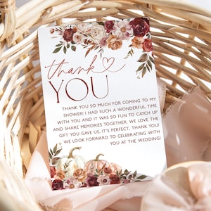 May include: A thank you card with a floral design in shades of red, orange, and white. The card has the text "thank you" in a copper color and a heart symbol. The text reads "Thank you so much for coming to my shower! I had such a wonderful time with you and it was so fun to catch up and share memories together. We love the gift you gave us, it's perfect, thank you! We look forward to celebrating with you at the wedding!"