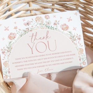 May include: A thank you card with a floral design and the text "thank you" in pink. The card has a message thanking guests for attending a baby shower and includes the name "Olivia".
