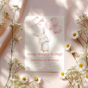 Op de afbeelding: Een roze en witte uitnodigingskaart met een aquarel-illustratie van een konijn dat ballonnen vasthoudt. De tekst op de kaart luidt "Some Bunny is One!" en "Isabella's 1st Birthday".
