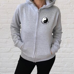 May include: A grey zip-up hoodie with a black yin yang symbol and the text "Channel the Chi" on the front.