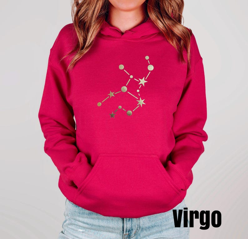 May include: A pink hoodie with a gold Virgo constellation design. The word "virgo" is printed in black at the bottom of the image.
