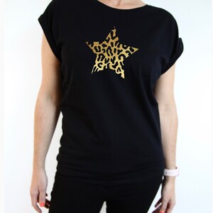 Pu&ograve; includere: Maglietta nera con una stampa a stella dorata con un design a stampa leopardata.